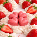 Close-up of a dessert with whipped cream, strawberries, and pink heart-shaped candies.