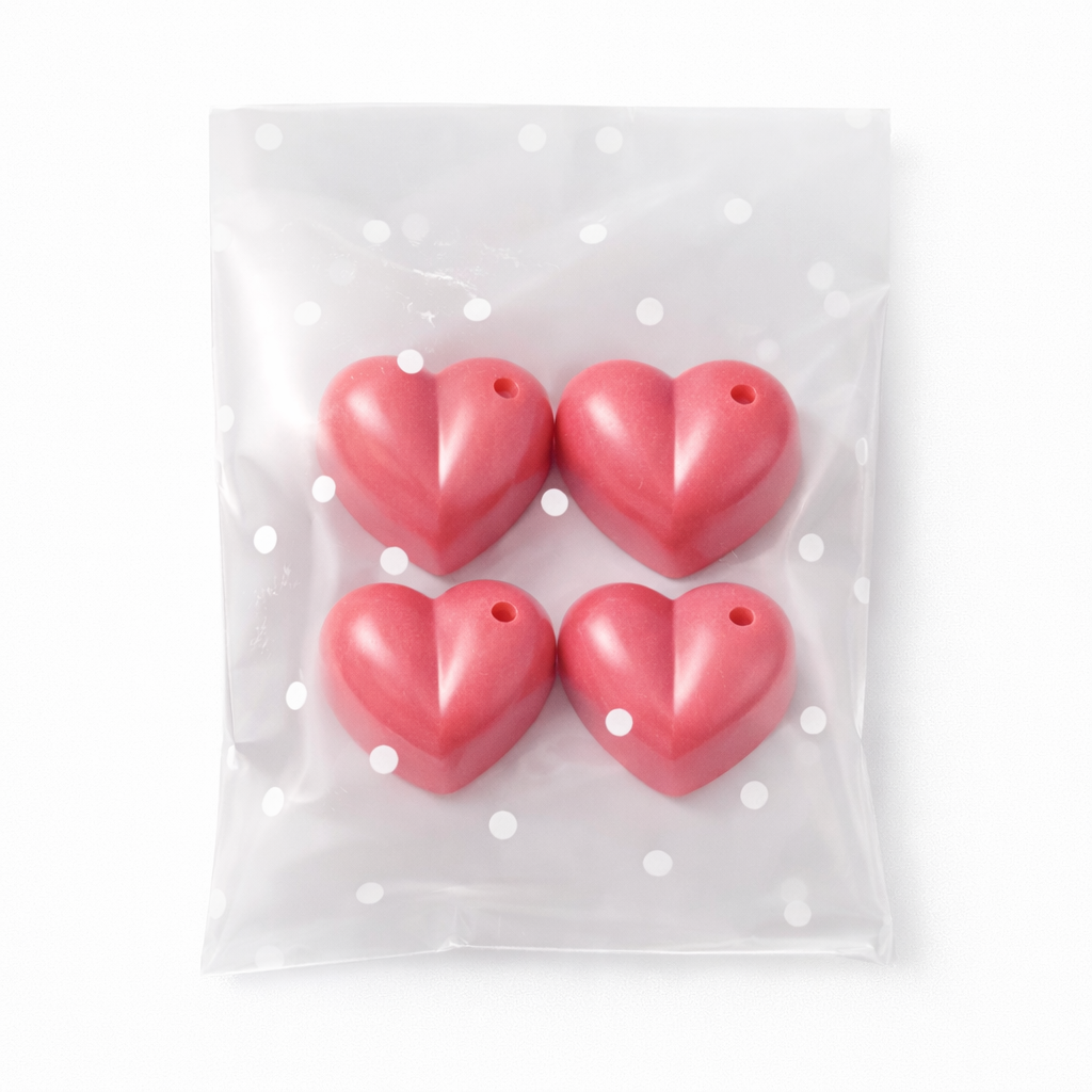 Four red heart-shaped wax melts in a clear plastic bag with white polka dots on a white background